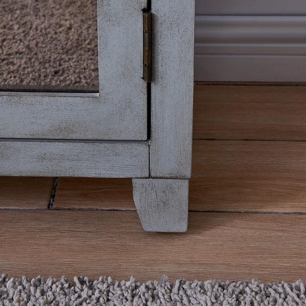 Close up of distressed wood cabinet leg with mirrored door on hardwood floor