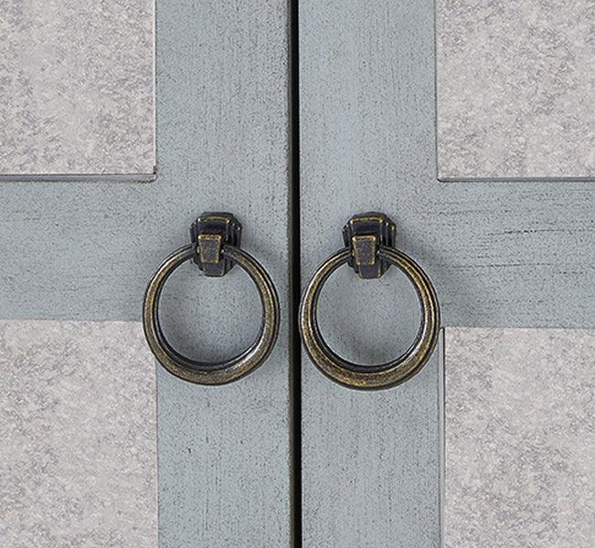 Closeup of wooden cabinet doors with antique brass ring handles and grey panel detail