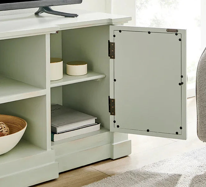Light sage TV unit with open cabinet door, shelves, storage jars, and stacked books