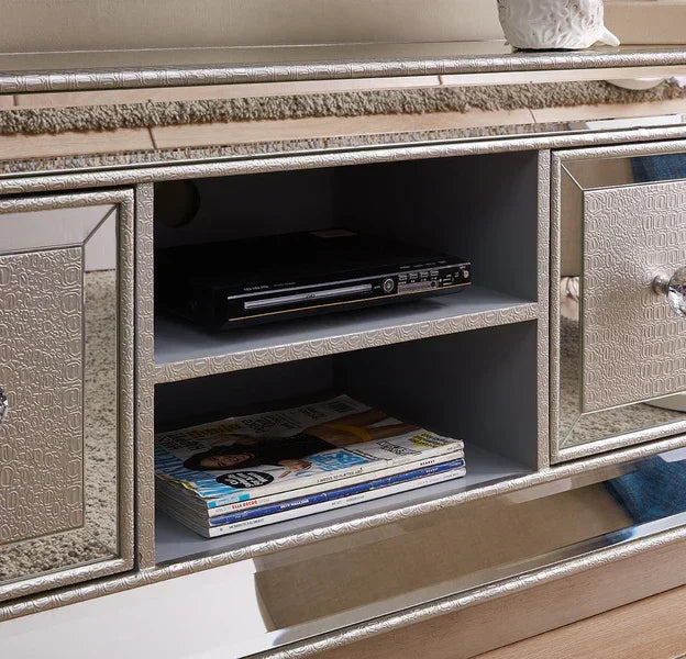 Mirrored TV unit with textured drawers, open shelves holding magazines and a media player