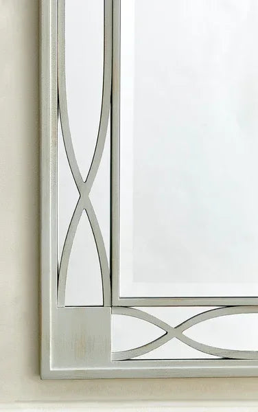 Rectangular wall mirror with silver frame and geometric metallic detailing in corner view
