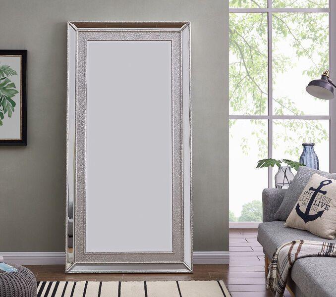 Large silver framed wall mirror leaning against living room wall beside sofa