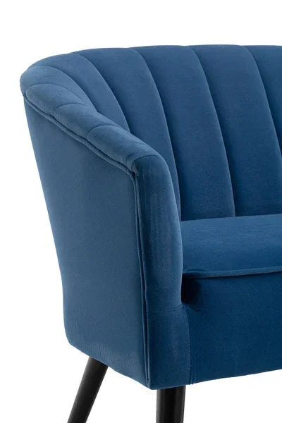 Blue velvet armchair with scalloped backrest and black angled legs, close-up view