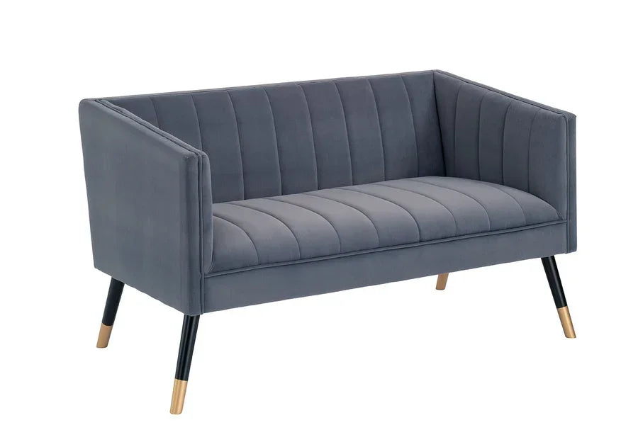 Grey velvet sofa with vertical tufting and gold-tipped black legs on white background