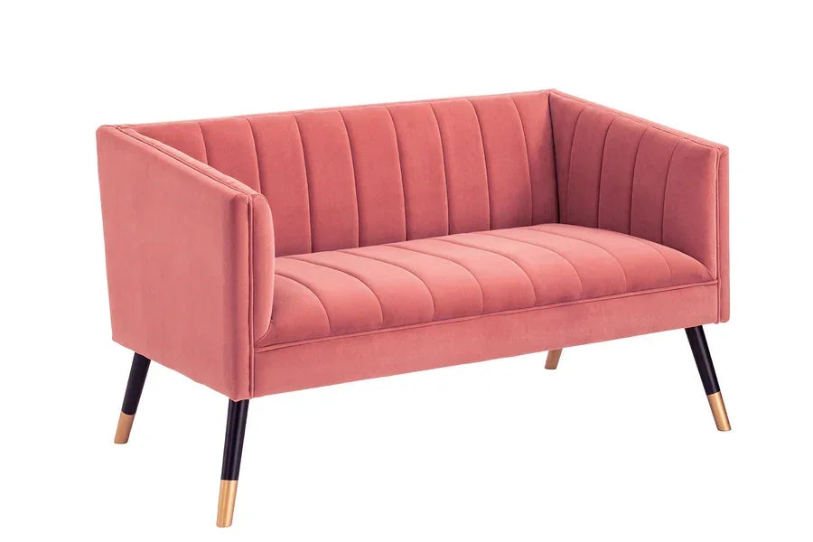 Pink velvet sofa with vertical channel tufting and angled black legs with gold tips