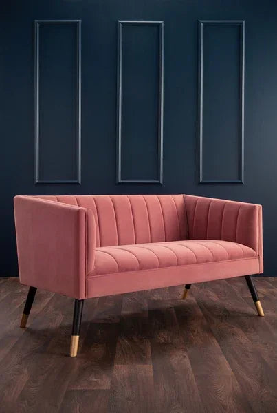 Pink velvet two seater sofa with vertical channel tufting and angled wooden legs