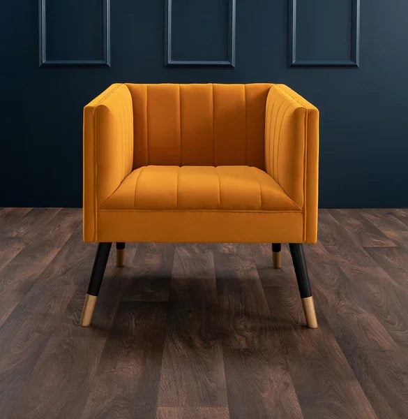 Mustard yellow velvet accent armchair with black legs on wood flooring