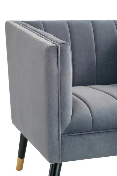 Grey velvet armchair with vertical stitched backrest and black tapered legs, close-up view
