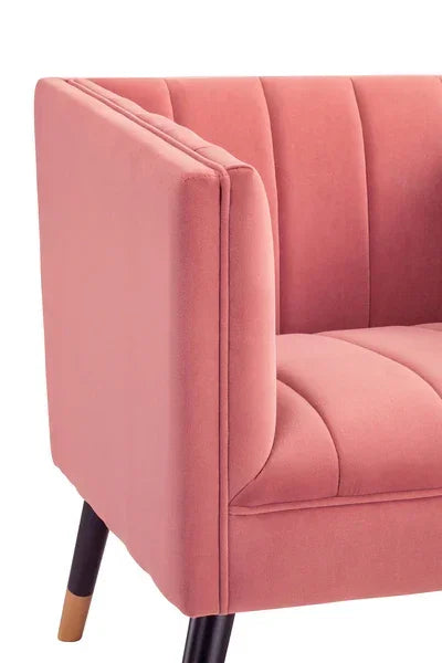 Closeup of pink velvet accent chair with vertical stitching and black wooden legs