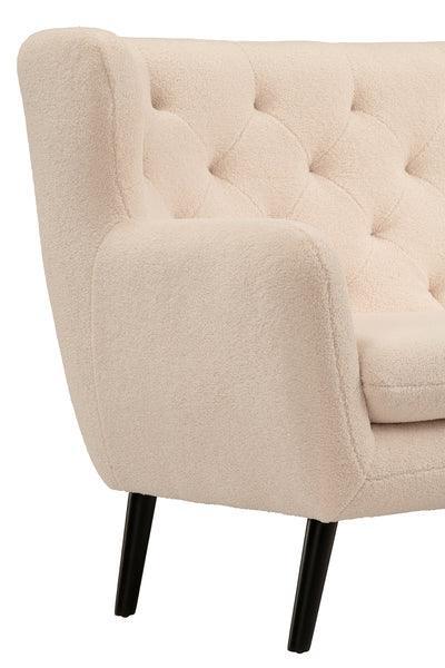 Cream fabric sofa with tufted backrest and black tapered legs, close-up of arm and seat