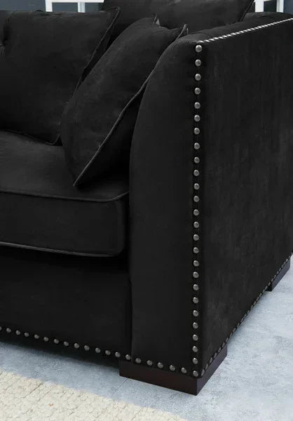 Black fabric sofa with nailhead trim and scatter cushions on light carpet