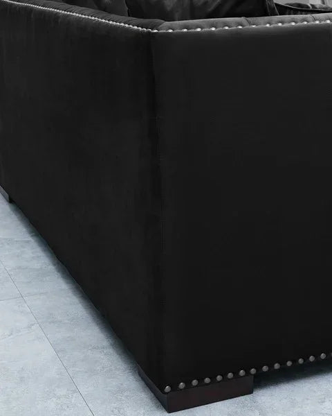 Black fabric sofa with studded trim and wooden legs on tiled floor