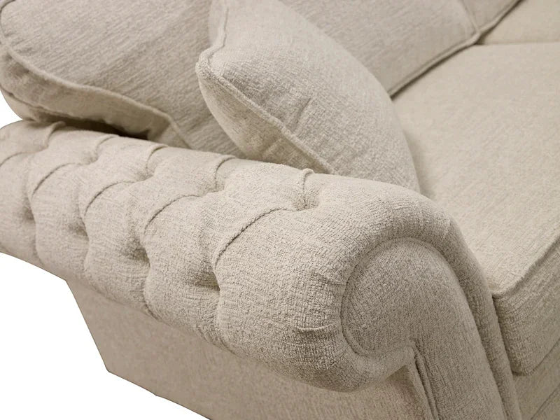 Beige fabric sofa with rolled armrest and tufted detailing close-up