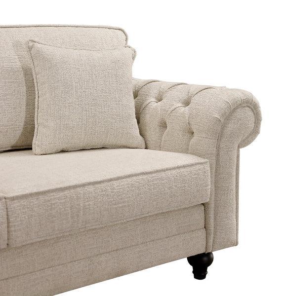 Beige fabric sofa with tufted armrest and matching cushion, close-up of left corner
