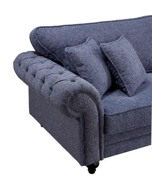 Blue fabric sofa with tufted armrest and matching scatter cushions, close-up angle