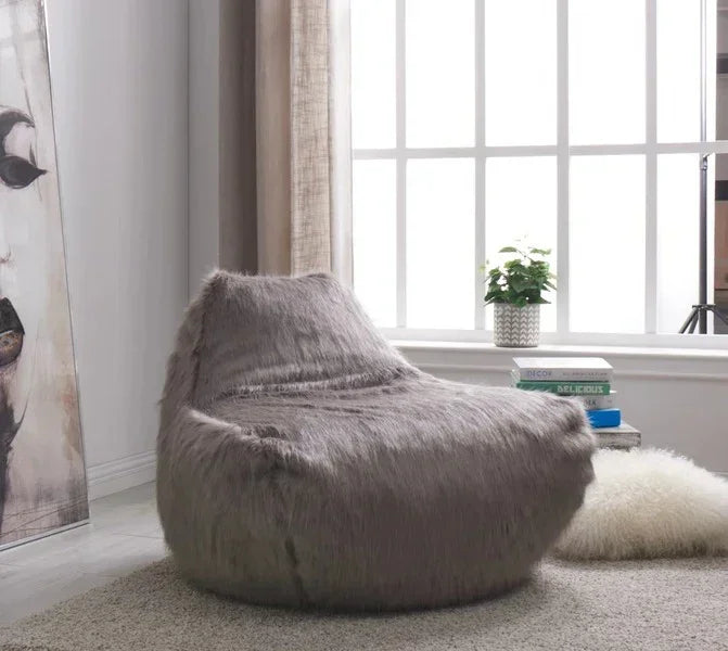 Grey faux fur bean bag chair in modern living room with large window and artwork