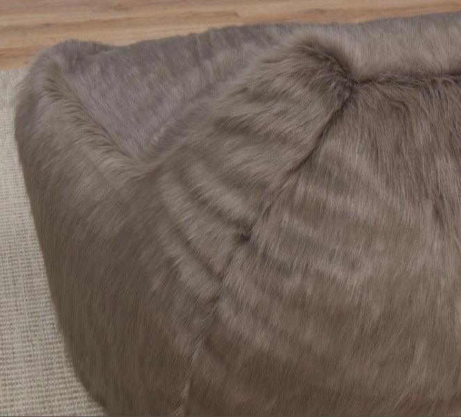 Taupe faux fur bean bag chair on textured rug and wood floor