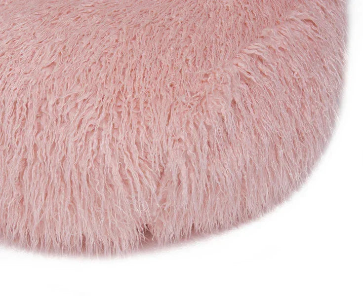 Round pink faux fur cushion with long pile texture, close-up view