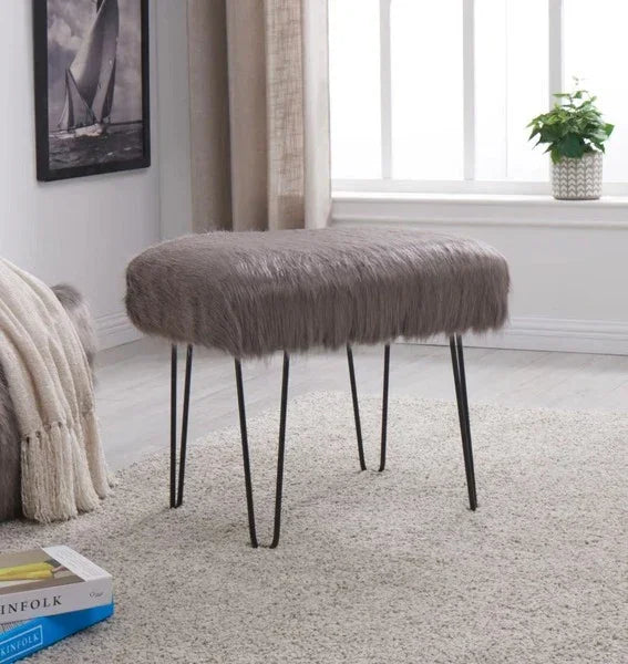 Grey faux fur stool with black metal hairpin legs on light carpet in living room setting
