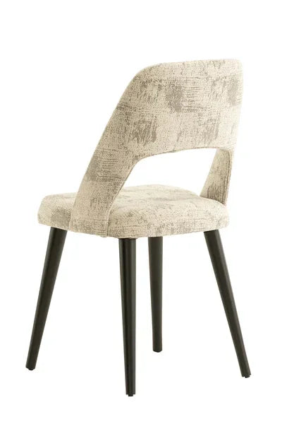 Beige fabric dining chair with cut-out back and black metal legs, rear side view