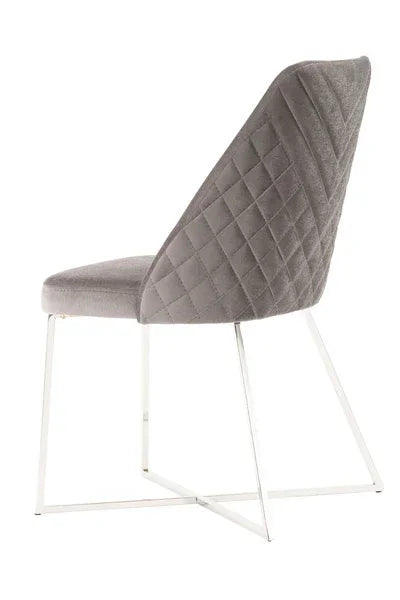 Grey velvet dining chair with quilted back and chrome metal legs, rear angled view