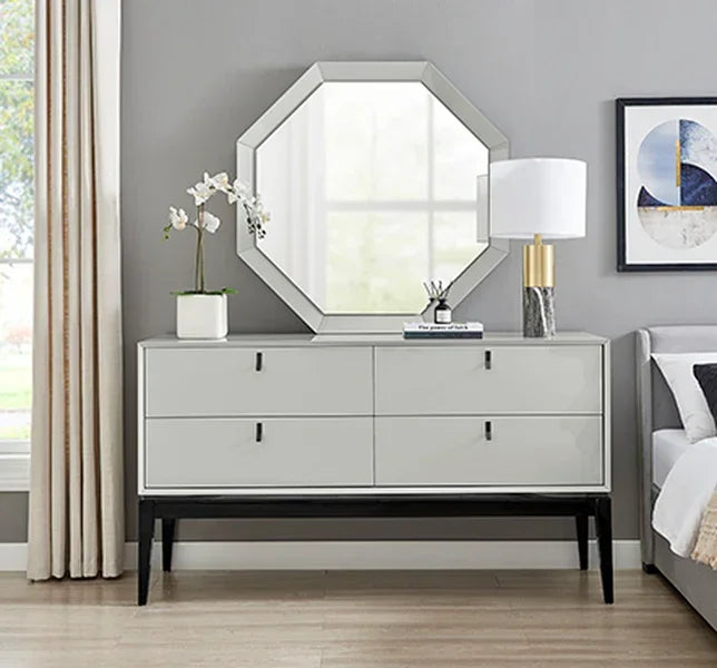 Modern grey sideboard with four drawers, octagonal mirror, lamp, and orchid plant