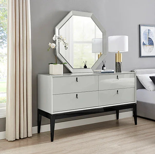 Glossy sideboard with four drawers, octagonal mirror, lamp and plant in modern living room
