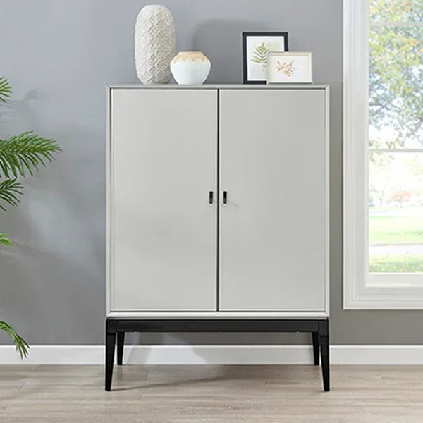 Modern grey storage cabinet with black legs against grey wall, decorative items on top