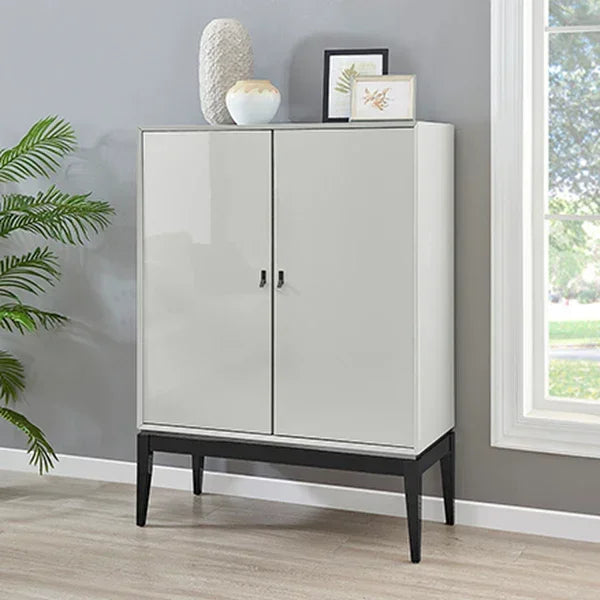 Glossy white storage cabinet with black legs in modern living room next to window