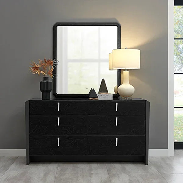 Black bedroom dresser with nine drawers, decorative vase, table lamp, and square wall mirror