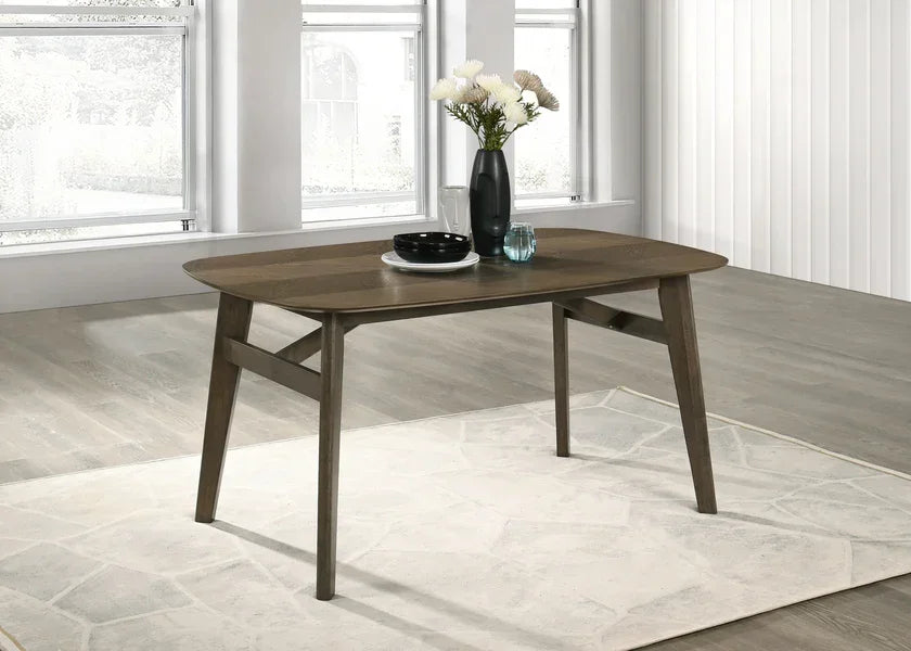 Rectangular wooden dining table with vase and dinnerware on light rug in modern room