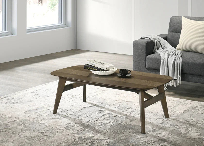 Modern wooden coffee table with books and cup beside grey sofa in living room