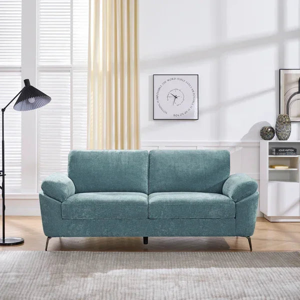 Light blue fabric sofa with slim black legs in a bright living room setting