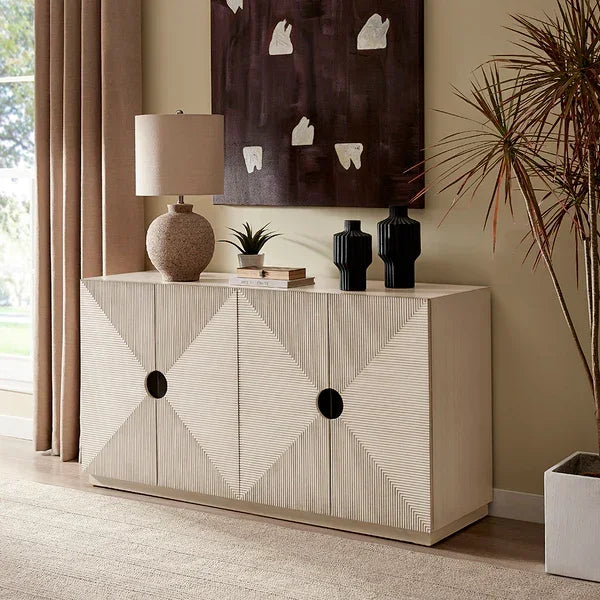 Cream sideboard cabinet with geometric pattern, black handles, lamp, and decor accents on top