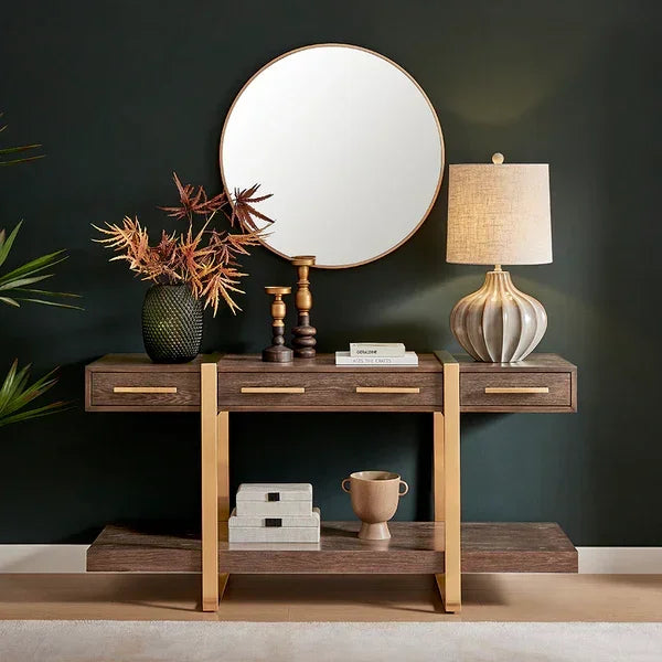 Modern wood console table with gold accents, table lamp, and round wall mirror in entryway