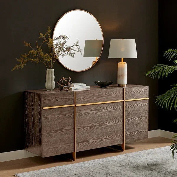 Modern wood sideboard with gold accents, round mirror, table lamp and decor in living room