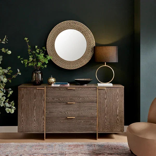 Modern sideboard with gold handles, round mirror and table lamp in stylish living room