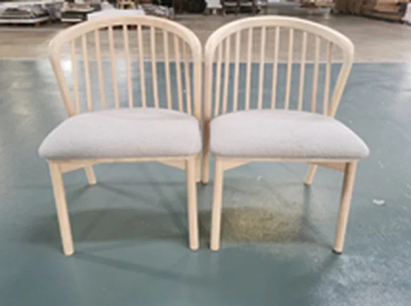 Pair of wooden dining chairs with curved spindle backs and light upholstered seats