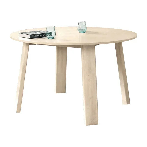 Round wooden dining table with light wood finish, two glasses and a book on top