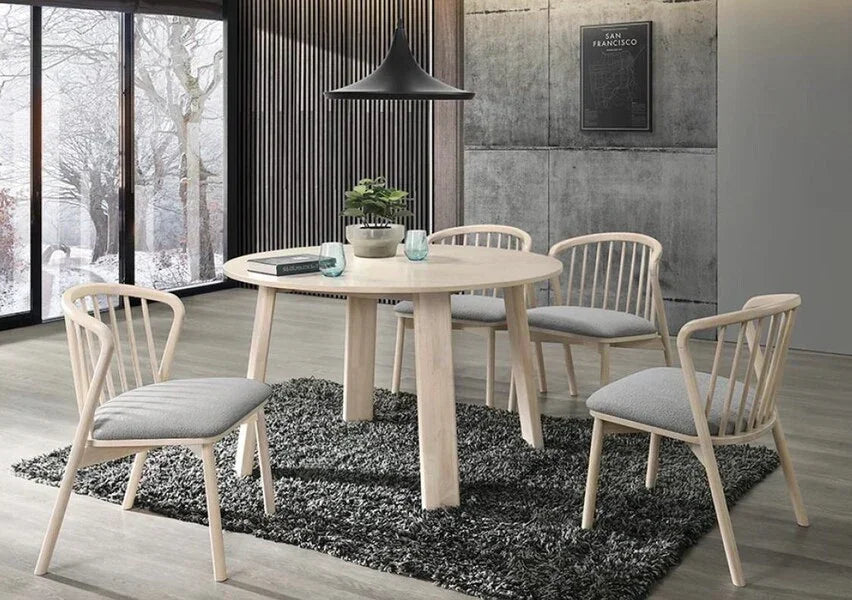 Light wood dining table with four grey cushioned chairs on a dark rug in modern dining room