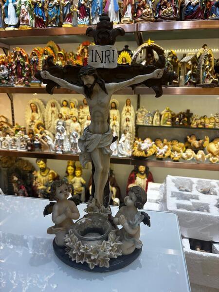 Crucifixion figurine with two cherubs and floral base on glass display in religious ornament shop