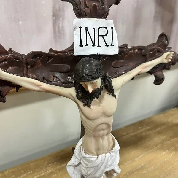 Resin crucifix sculpture with INRI plaque on wood grain table