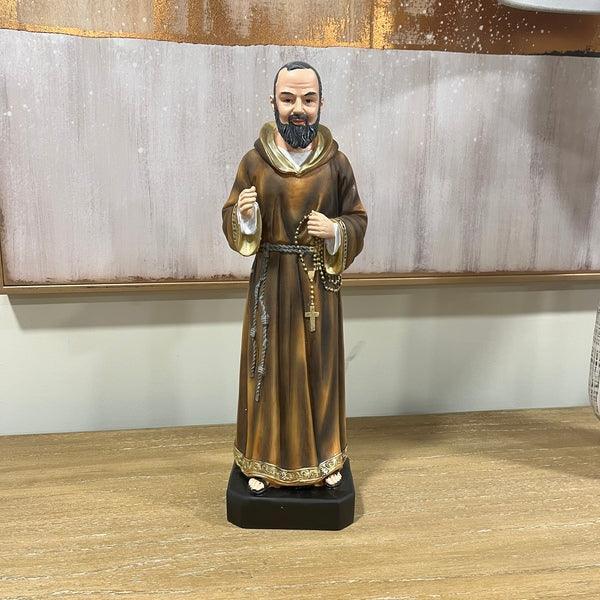 Brown robed religious figurine with rosary on wooden table against neutral wall art