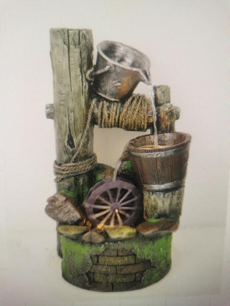 Rustic garden water feature with wheel, wooden buckets, and mossy stone base