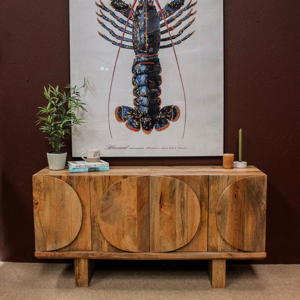 Wooden sideboard with oval door designs against dark wall with lobster artwork