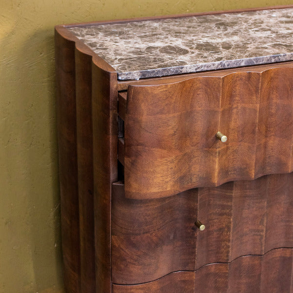 Close-up of wooden cabinet drawers with brass handles and marble top