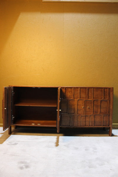 Wooden sideboard with two open doors showing interior shelves and carved front panels