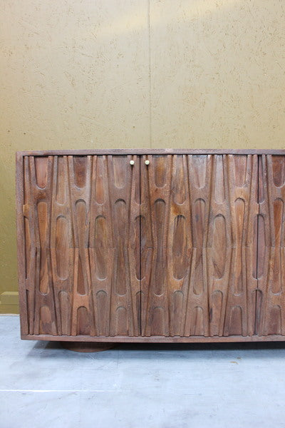 Wooden sideboard with carved abstract design and two small round handles