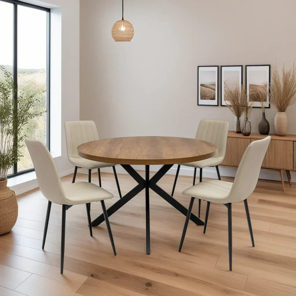 Round wood dining table with black metal legs and four cream chairs in modern room