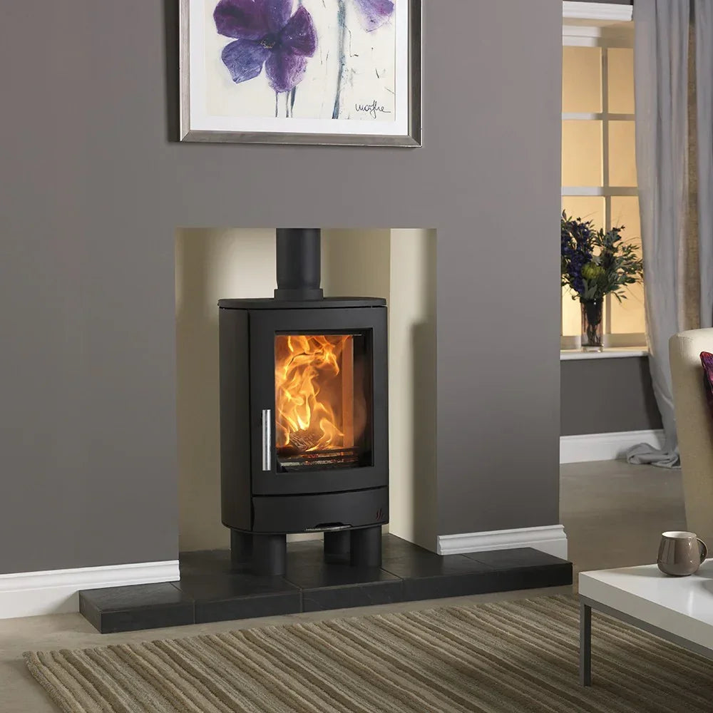 Black wood burning stove with glass door on black tile hearth in modern living room